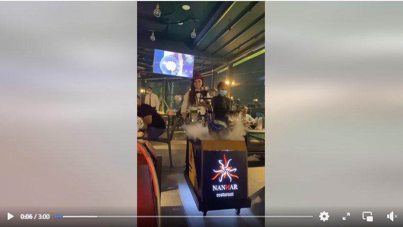 ظهور اسم المطعم على العربة التي تجرها النادلة التي تقدم الأركيلة بطريقة فنية في بغداد - العراق